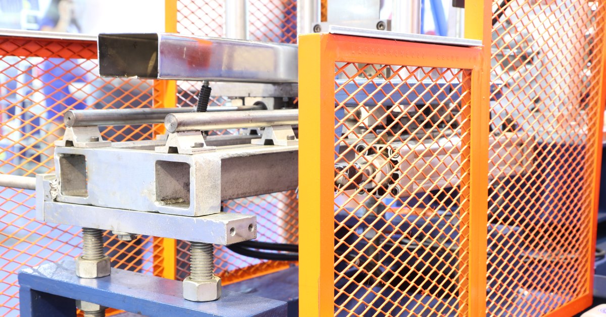 A close-up of orange machine guarding being used for a cold rolling machine. The guard surrounds the machine.