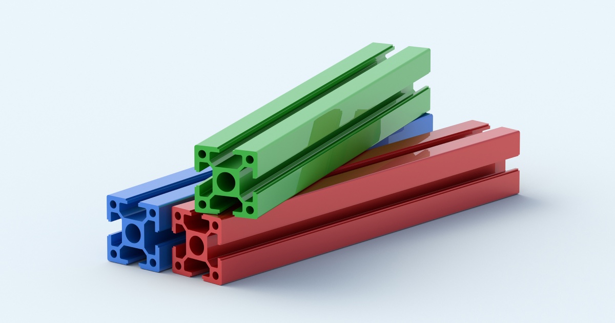 Three aluminum profiles stacked on top of each other in front of a plain background. Each profile is a different color.