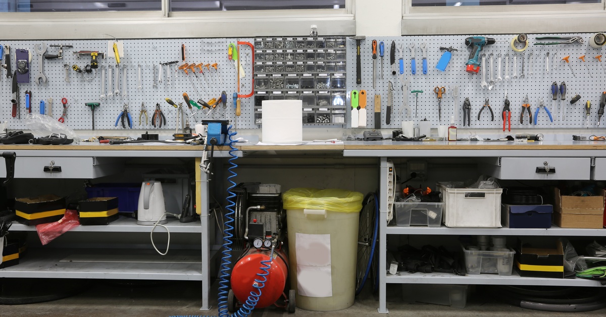 A large workbench with tools set up on a pegboard above the desk. Below the desk are shelves holding equipment.