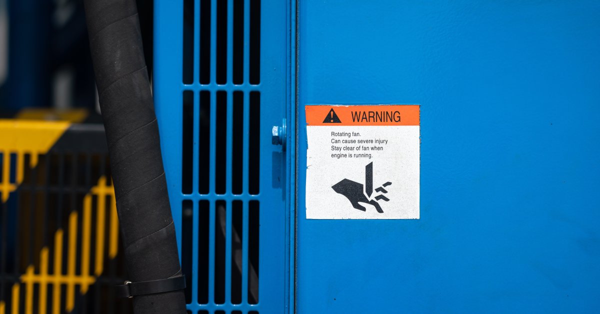 A safeguard plate for a power generator engine. The plate also has a warning sign with an image of a hand being crushed.